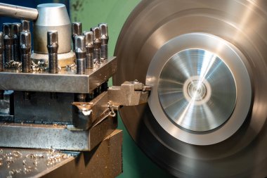 Torna makinesi metal disk parçalarını torna tezgahıyla kesiyor. Makineyi döndürerek metal işleme süreci.