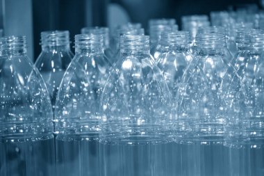 İçme suyu fabrikasındaki işlemleri tamamlamak için konveyör bandındaki boş PET şişeleri. Plastik şişe üretim sürecinin yüksek teknolojisi..