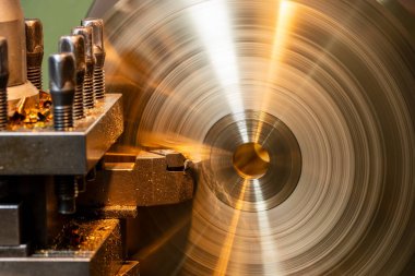 Torna makinesi, torna tezgahıyla pirinç disk parçalarını kesiyor. Makineyi döndürerek metal işleme süreci.