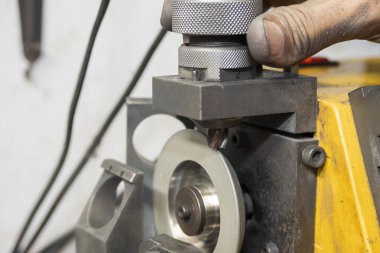 İşçi son değirmen bileme makinesi ile son değirmen aletini yeniden öğütüyor. Makine operatörü tarafından kesme araçları yeniden öğütme işlemi.