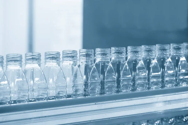 İçme suyu fabrikasındaki işlemleri tamamlamak için konveyör bandındaki boş PET şişeleri. Plastik şişe üretim sürecinin yüksek teknolojisi..