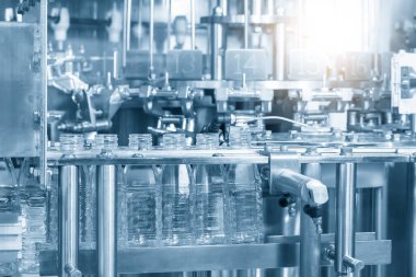 İçme suyu fabrikasındaki işlemleri tamamlamak için konveyör bandındaki boş PET şişeleri. Plastik şişe üretim sürecinin yüksek teknolojisi..