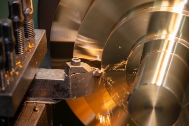 Torna makinesi, torna tezgahıyla pirinç disk parçalarını kesiyor. Makineyi döndürerek metal işleme süreci.