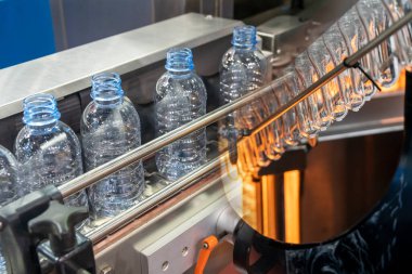 İçme suyu fabrikasındaki PET şişelerinin işlendiği soyut sahne. Plastik şişe üretim sürecinin yüksek teknolojisi..