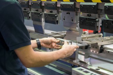 Hidrolik fren bükme makinesiyle çalışan operatör. Yetenek operatörünün kullandığı levha metal çalışması.