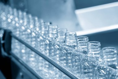 İçme suyu fabrikasındaki işlemleri tamamlamak için konveyör bandındaki boş PET şişeleri. Plastik şişe üretim sürecinin yüksek teknolojisi..