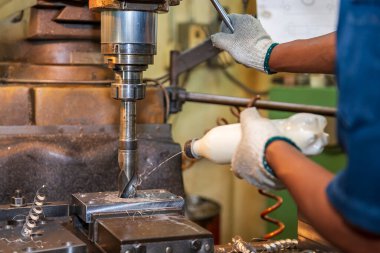 Makine operatörü, matkap aletini NC değirmen makinesiyle su bazlı soğutucu ile soğutuyor. NC değirmen makinesinin atölye çalışması.