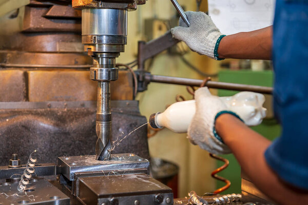 The machine operator cooling the drill tool by water base coolant with NC milling machine. The shop floor operation by NC milling machine.