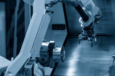 CNC torna makinesinin metal parçalarını tutan otomatik robot kolu. Dönüşüm makinesinde robotik sistem tarafından yüksek teknoloji materyal işleme süreci. 