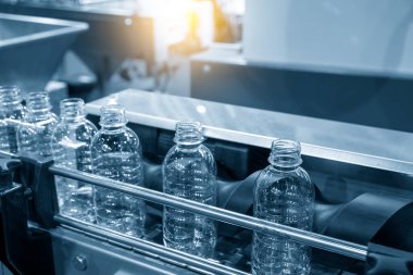 Taşıyıcı banttaki boş içme suyu şişeleri doldurmak için. İçme suyu üretim sürecinin yüksek teknolojisi.