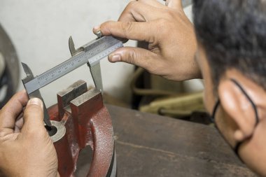 Close up scene the operator measuring metal shaft parts by  Vernier caliper. The quality control on turning machine. 