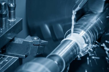 The lathe machine cutting the metal shaft parts with coolant method. The metalworking process by turning machine.