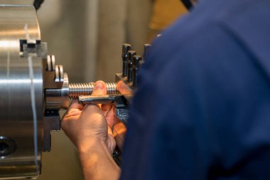 Operatör, metal şaft parçalarını yerleştirir. Dönüş makinesinin kalite kontrolü. 