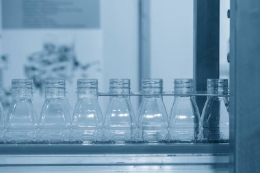 Taşıyıcı banttaki boş su şişelerini doldurmak için kapatın. İçme suyu üretim sürecinin yüksek teknolojisi.