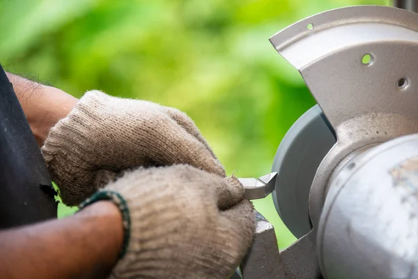 İşçi makyaj tekeriyle torna takımını yeniden öğütüyor. Makine operatörü tarafından kesme araçları yeniden öğütme işlemi.