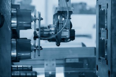 The robotic arm gripping the plastic cup from the injection machine. The high technology automatic operation in injection mold processing.