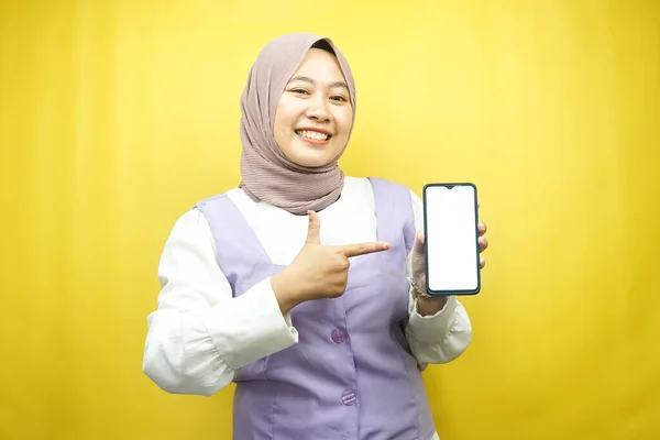 美しい若いアジアのイスラム教徒の女性は スマートフォンを指して手を自信を持って 熱狂的かつ陽気に笑みを浮かべて 何かを促進し 手のアプリを促進し 黄色の背景に孤立し 広告コンセプト — ストック写真