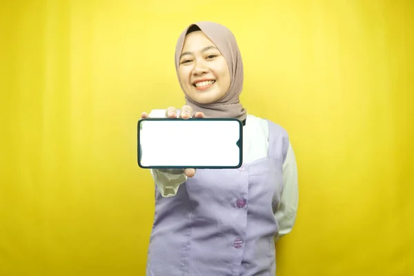 自信を持って笑顔美しい若いアジアのイスラム教徒の女性 手をスマートフォンを保持して熱狂的かつ陽気です アプリケーションを促進します ゲームを促進します 黄色の背景に孤立 広告コンセプト — ストック写真
