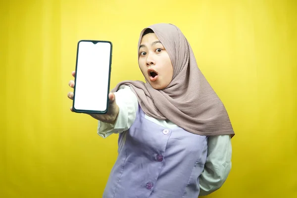 美しい若いアジアのイスラム教徒の女性はショックを受け すごい表情 空白の画面でスマートフォンを手に持ち アプリを宣伝し 製品を宣伝し 何かを提示し 黄色の背景に隔離された — ストック写真