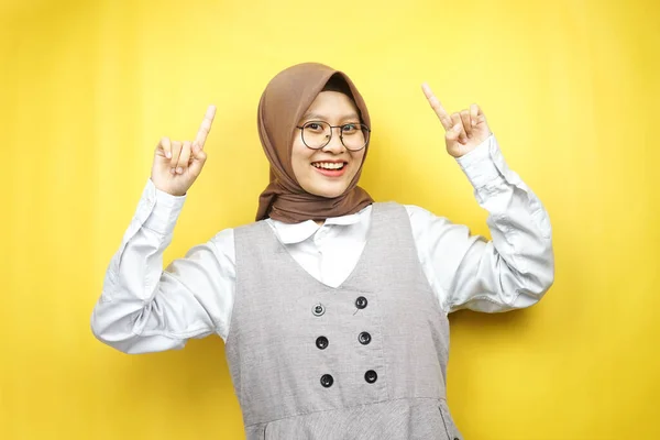 美しい若いアジアのイスラム教徒の女性は 黄色の背景に隔離されたカメラを見て 何かを提示する手で自信を持って 熱狂的かつ陽気な笑顔広告コンセプト — ストック写真
