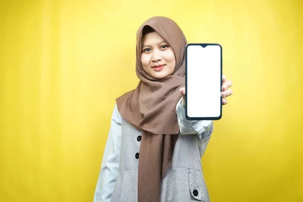 美丽的年轻亚洲穆斯林女子面带微笑 充满热情和欢乐 手拿着智能手机 推销某事 手拉着应用程序 被黄色背景隔离 做广告概念 — 图库照片