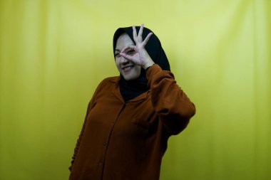 Güzel ve neşeli Asyalı genç Müslüman kadın, dürbün elleriyle, bir şeye bakıyor, izole edilmiş.