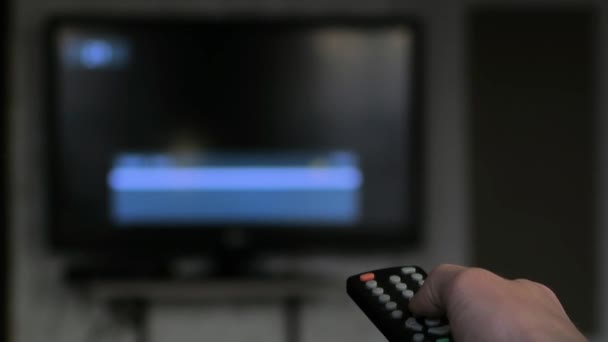 Canali interruttore a mano tramite telecomando. TV sfocata, mano da vicino — Video Stock