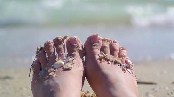 Vrouw voeten liggend op het zomerstrand bij zonsondergang van dichtbij. Zomervakantie — Stockvideo