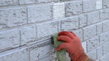 Construction worker cleaning up insulation sheets on house facade wall