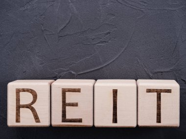 Gri beton arkaplanda tahta bloklar üzerinde metin REIT