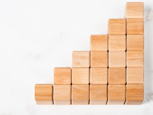 Wood cubes stack in graph shape as metaphor to business growth
