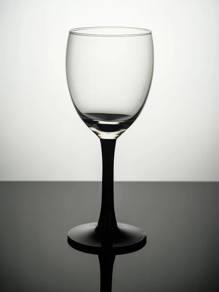 An empty shot glass with a black leg stands on a gray table