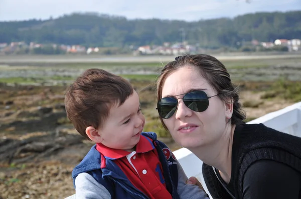 Beautiful son is happy looking at his young mother. He is proud of her. Both are enjoying the day in the green countryside
