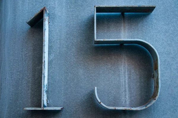 Old retro weathered metal stainless steel cold blue plate with number 15. Vintage dirty weathered symbol
