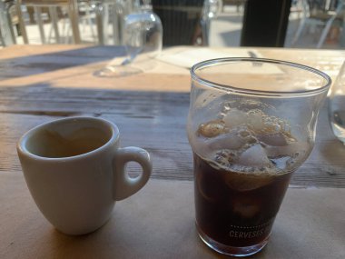 Organic black coffee mixed with ice over a wooden restaurant table. A pleasure to battle hot weather.