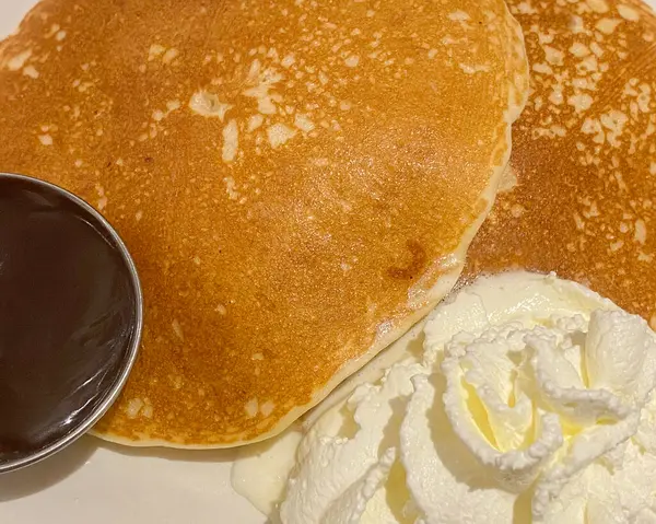 Pancakes with chocolate syrup and white cream. Close up top view