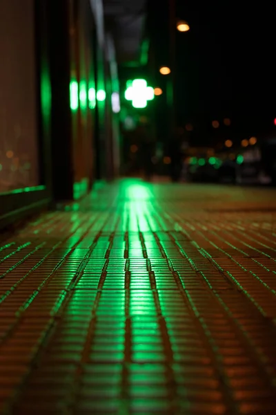 Urban background. Lights shadows and reflections in a street. Green strong light from reflected on the ground.