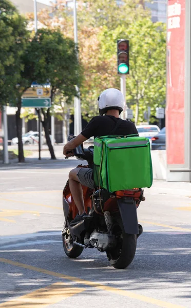 Food delivery moto scooter driver with green backpack behind back is on his way to deliver food. Courier on scooter delivering food. Quick shipping of goods to customers.