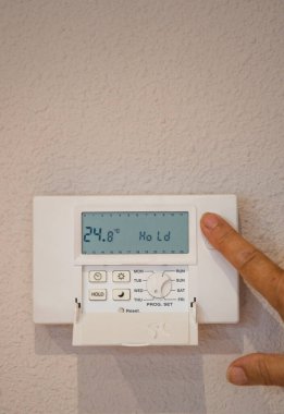 Evdeki Dijital Termostat 'ın duvardaki ısısını ayarlayan kişinin yakın çekimi. Boşluğu kopyala.