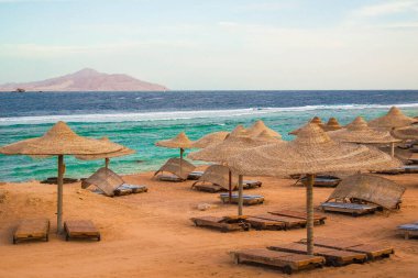 Düşük mevsimlerde güverte sandalyeli ve şemsiyeli kumsal