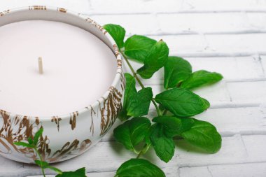 Bir mum beyaz tuğla bir yüzey üzerinde duruyor, bir nane, bir kaplıca salonu, spa tedavileri