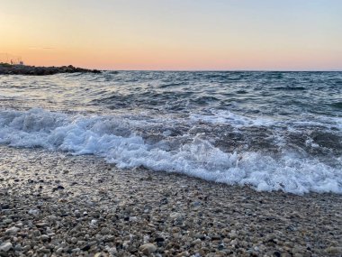 Gün batımında deniz dalgaları, su sıçramaları, deniz arka planı.