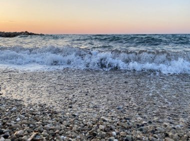Gün batımında su sıçramasıyla deniz dalgaları.