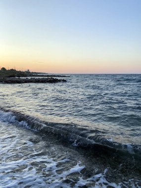 Denizin üzerinde gün batımı, kayalık plaj