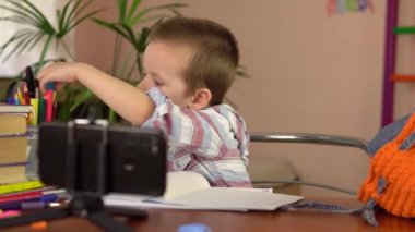 Anaokulundan bir çocuk mavi keçeli kaleminin kapağını çıkarıp derse hazırlanıyor..