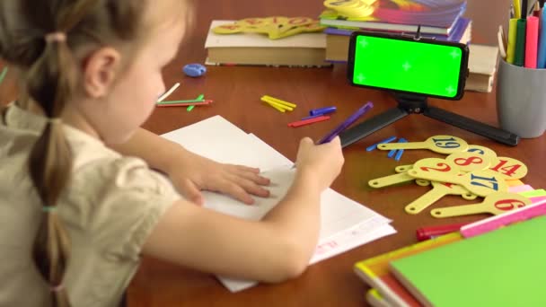 Kis iskoláslány alszik az asztalnál egy okostelefon zöld képernyővel.Távolság tanulás. — Stock videók