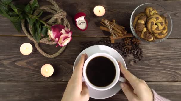 Egy nő vesz egy fehér csésze kávét egy romantikus díszítésű asztalról Valentin-napra. — Stock videók