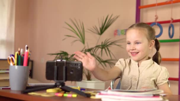 Hermosa niña preescolar agita la mano al maestro, mirando al teléfono inteligente. — Vídeos de Stock