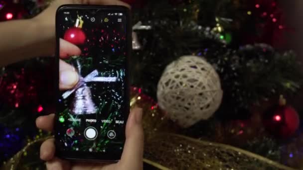 Uma mão feminina faz uma foto de uma árvore elegante de Natal usando um smartphone.Photo para redes sociais — Vídeo de Stock