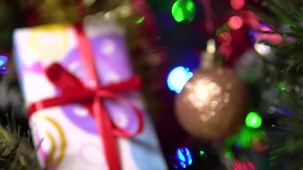 Красивый блестящий шар и подарочная коробка висят на дереве. Размытый фон рождественской елки. — стоковое видео
